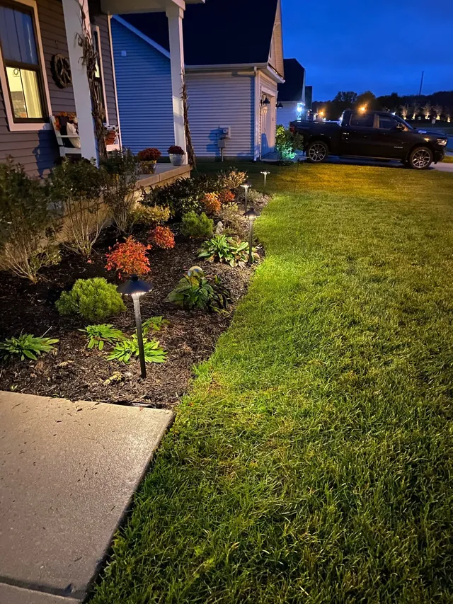 Paver patio and fire pit with landscape lighting at night