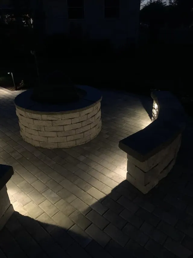 Stone fire pit and seat wall with landscape lighting