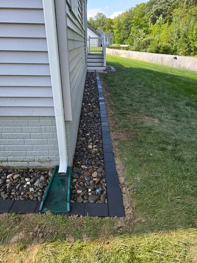 French drain rock trench along a side yard foundation