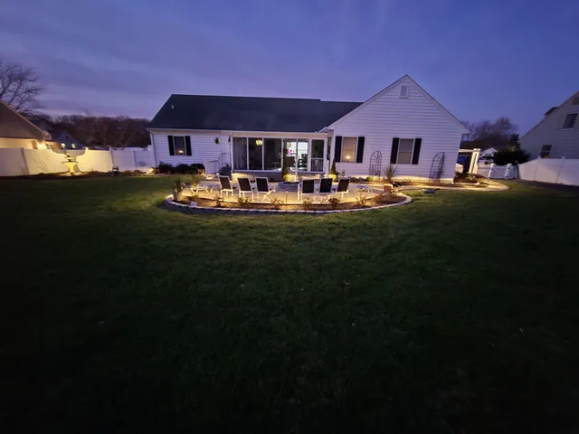 Landscape lighting around a backyard patio seating and fire pit area