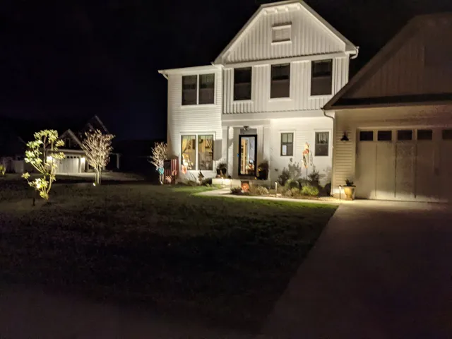 Landscape lighting installation on a farmhouse at dusk