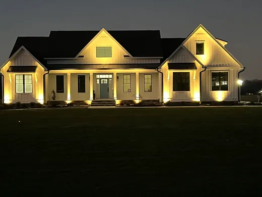 Landscape lighting installation lighting up a home's exterior at night — Elzey Services