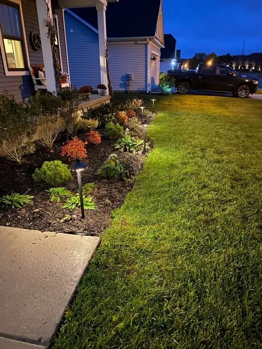 Path lights along a mulch bed and lawn at dusk