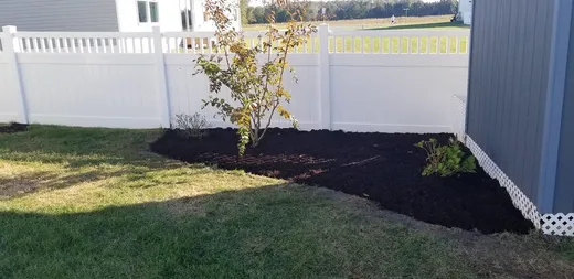 Freshly mulched landscape bed along a fence line — Elzey Services
