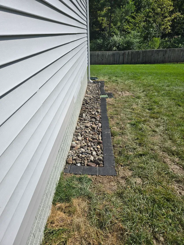 Paver patio and porch post next to a drainage bed