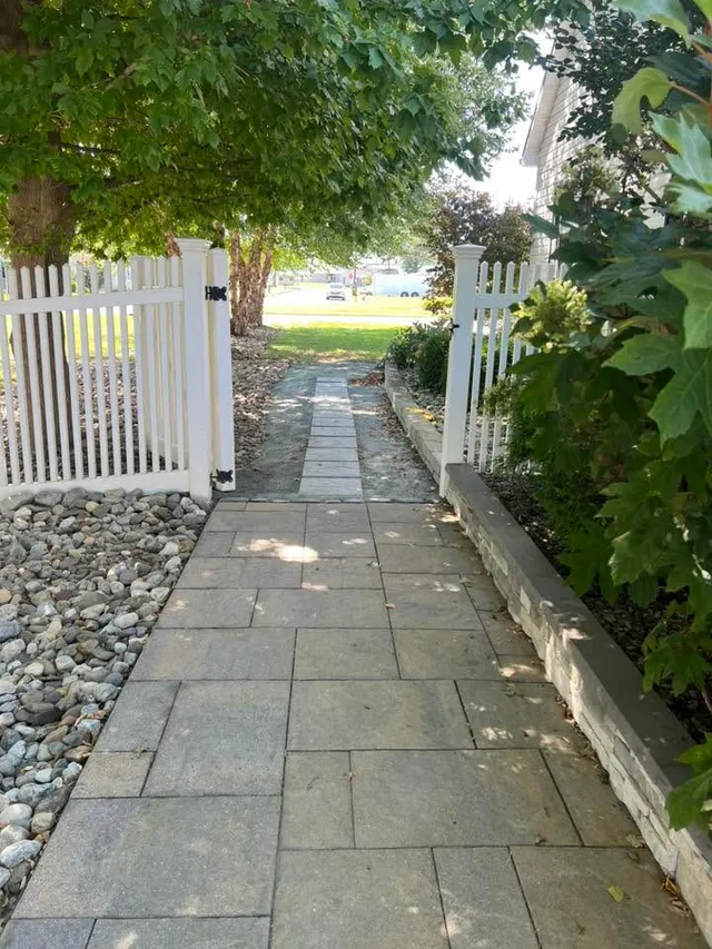 Paver walkway leading through a garden gate