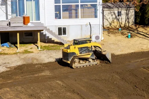 Skid steer grading and leveling a yard